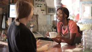 smiling cashier handing coffee to customer
